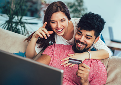 Man using laptop and woman holding credit card. Young couple shopping online with credit card at home